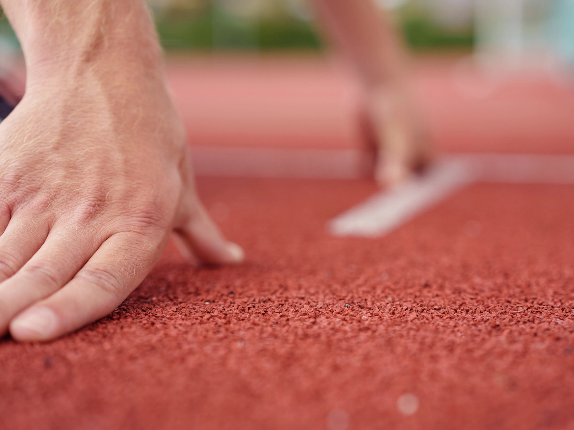 Finger einer sprintenden Person an der Startlinie in Nahaufnahme.
